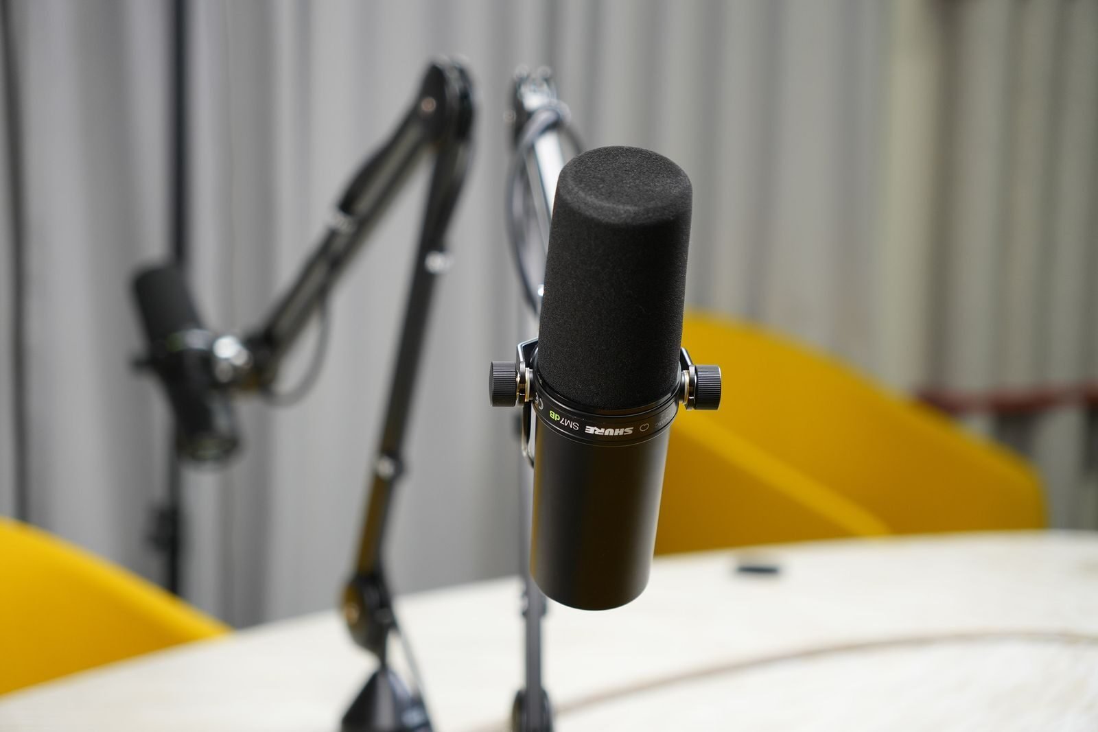 Photo by Jakub Zerdzicki Close-up of a dynamic microphone in a modern podcast studio setup with boom arms.
